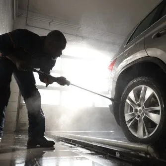 Detailer pressure-washing the exterior of an SUV